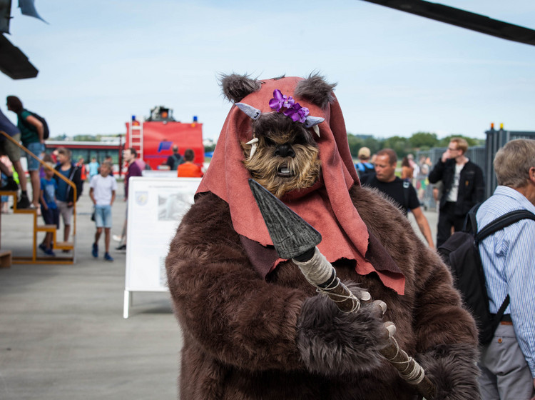 Star-Wars-Kostüm auf dem Rollfeld Eine Person in Star-Wars-Verkleidung im Vordergrund und mehrere Personen im Hintergrund auf dem Rollfeld.