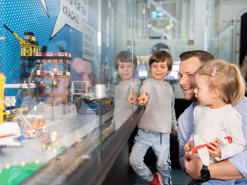Ein Vater und zwei Kinder betrachten Ausstellungsstücke im Dornier Museum.